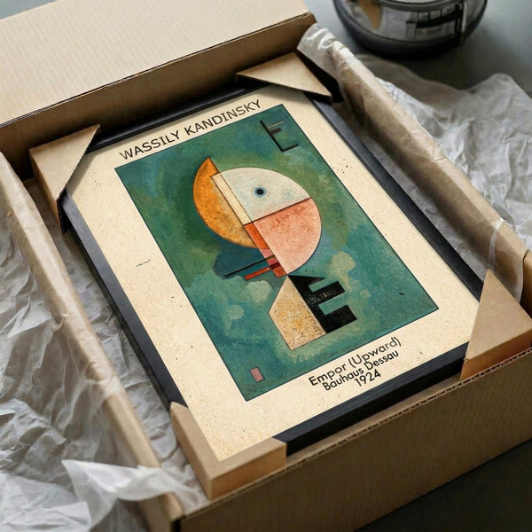 May include: Framed Kandinsky abstract art print in protective packaging within cardboard shipping box. The artwork features geometric shapes in orange, coral, and white against a teal-green background, with "Empor (Upward) Bauhaus Dessau 1924" text below. Cream matting surrounds the print in black frame, nestled in white tissue paper.