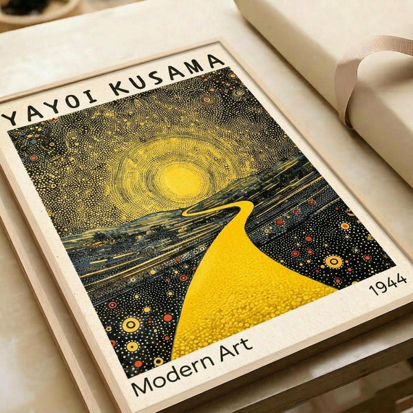 May include: Framed art print featuring Yayoi Kusama's distinctive pointillist style with bright yellow sun radiating concentric circles, winding yellow path through cosmic dark landscape dotted with colorful orbs, displayed on white surface with cream ribbon nearby