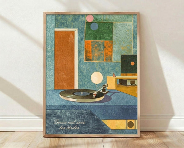 May include: Framed abstract geometric art print featuring a vintage turntable on a blue textured surface surrounded by colorful rectangular shapes in orange, green, and teal. The composition includes circular elements in pink, blue, and cream, with French text at the bottom reading "Douce nuit sous les étoiles". The artwork has a mid-century modern aesthetic with layered geometric forms and muted vintage colors, displayed in a light wood frame against a white wall on wooden flooring.