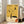 May include: Abstract art poster with yellow and cream background featuring geometric shapes, curved lines, and celestial elements like a crescent moon. Text reads "Artistic Expression" and "A World of Forms" at top. Displayed in white frame leaning against wall next to beige armchair in bright, minimalist living room with large windows.