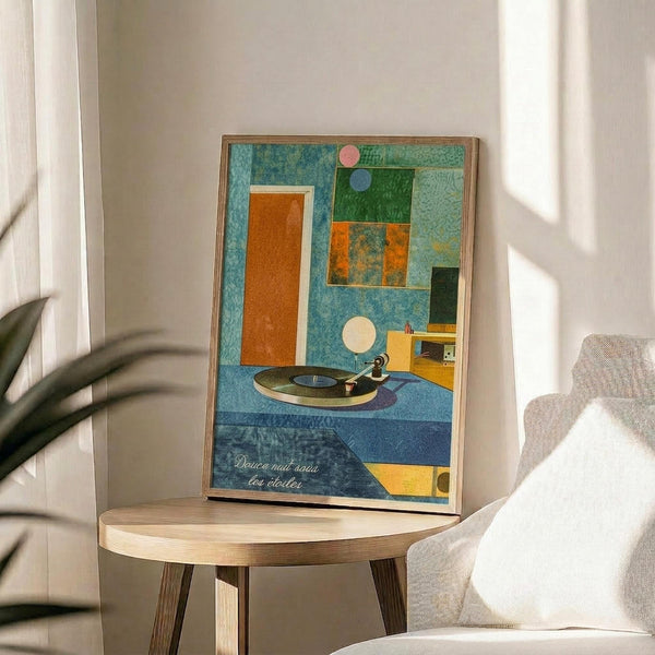 May include: Colorful abstract art print featuring geometric shapes in blue, orange, and green tones with a vinyl record player centerpiece. The framed poster sits on a round wooden side table next to a beige upholstered chair in a bright, minimalist room with white walls and natural lighting. Plant leaves visible in corner add organic contrast to the modern geometric artwork.