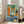 May include: Framed abstract art print featuring a vintage turntable surrounded by geometric shapes in blues, greens, oranges and yellows with French text at bottom, displayed on wooden floor next to beige sofa in bright living room with white walls and windows