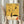 May include: Person in cream ruffled sleeves holding framed abstract art poster with yellow background featuring black geometric shapes, colorful circles, crescent moon, and Joan Miró-inspired elements. Light wooden frame against neutral curtained background with dried pampas grass visible on left side.