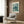 May include: Framed poster featuring a detailed illustration of a sea turtle swimming among coral and marine plants in teal and green tones, displayed on wood-paneled wall above beige upholstered armchair with geometric throw pillow. Modern floor lamp and side table with open book complete the contemporary living room setting.