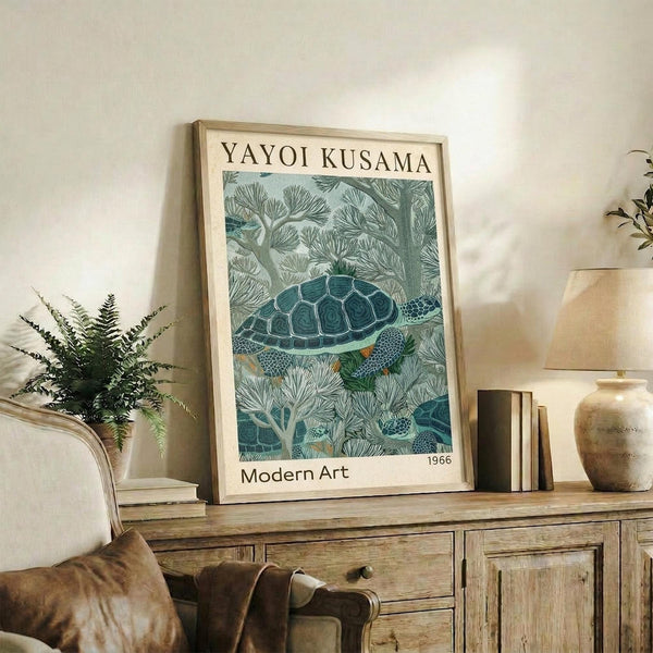 May include: Framed art print featuring a detailed sea turtle swimming among coral-like vegetation in muted blue-green tones, displayed on a rustic wooden sideboard alongside books, a ceramic vase, and fern plant in a cozy living room setting with cream walls and brown leather furniture