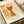 May include: Stylized orange cat artwork with yellow eyes and curved tail displayed as framed print on white mat board. The abstract feline figure features pointed ears and whiskers against weathered golden background with scratched texture. Print shows "PAUL KLEE" text and "La danse des couleurs Switzerland" below image, with "1924" in corner. Mat sits on neutral surface next to rolled white paper.