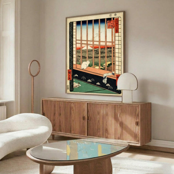 May include: Japanese woodblock print artwork displayed above wooden sideboard in modern living room. Print shows traditional interior view through wooden window frame overlooking Mount Fuji landscape, with white cat on windowsill and green tatami floor. Room features white curved chair, glass coffee table, and minimalist decor with warm wood tones throughout.