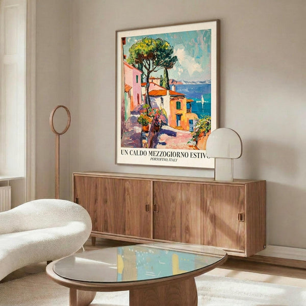 May include: Framed vintage-style poster featuring colorful Mediterranean coastal scene with pastel buildings, leafy tree, and blue water, displayed above wooden sideboard in modern living room with white upholstered chair, glass coffee table, and neutral decor