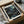 May include: Framed art print featuring a cosmic night sky with swirling teal and blue galaxies, scattered cream and white dots resembling stars and planets against a dark starry background. The print sits in a cardboard shipping box with protective tissue paper and wooden dowels for poster tube packaging. Black frame visible around the artwork.