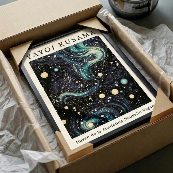 May include: Framed art print featuring a cosmic night sky with swirling teal and blue galaxies, scattered cream and white dots resembling stars and planets against a dark starry background. The print sits in a cardboard shipping box with protective tissue paper and wooden dowels for poster tube packaging. Black frame visible around the artwork.