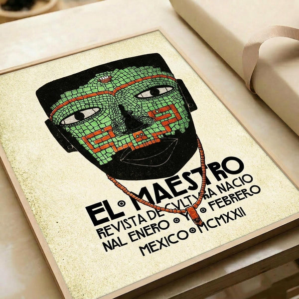 May include: Framed art print featuring a stylized green mosaic-patterned mask with red geometric accents and white eyes, displayed in a light wooden frame on cream paper. Spanish text below reads "EL MAESTRO" with publication details including Mexico and Roman numerals. The print has a vintage poster aesthetic with earthy tones, shown alongside rolled paper tubes on a light wooden surface.