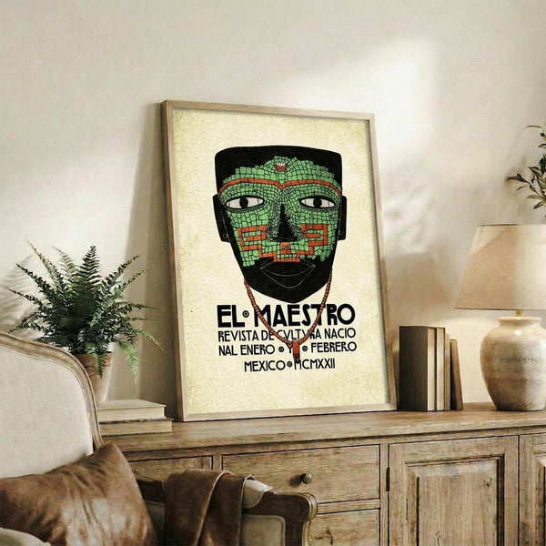 May include: Framed vintage-style poster featuring mosaic mask face in green tiles with red accents and Spanish text, displayed on rustic wooden sideboard with books, ceramic vase, and fern plant in neutral-toned living room setting