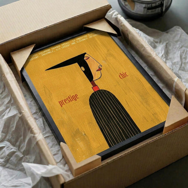 May include: Vintage-style French poster with yellow background featuring stylized black-haired woman's profile and the words "prestige" and "chic" in red text. Framed artwork shown in open cardboard shipping box with protective tissue paper wrapping and wooden dowels for secure packaging.