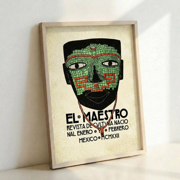 May include: Framed vintage-style poster leaning against white wall featuring an Aztec mosaic mask in green and red tiles with geometric patterns. The mask has white eyes and is set against black background. Spanish text below reads "EL MAESTRO REVISTA DE CULTURA NACIO NAL ENERO FEBRERO MEXICO MCMXXII" in bold black letters. Light wood frame with cream textured matting creates museum-quality presentation.