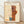 May include: Framed Paul Klee abstract artwork print displayed against white wall on wooden floor. The poster features geometric shapes in warm oranges, browns, and blue tones with linear pencil drawings on aged cream paper background. Light wooden frame surrounds the vintage-style reproduction with "Switzerland 1924" text at bottom. Natural lighting creates soft shadows on the wall.