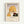 May include: Framed vintage-style art print showing a woman in golden yellow head wrap smelling a deep red rose against a soft purple-gray background. The minimalist illustration uses warm earth tones and geometric shapes. Light wood frame with cream matting displays the poster on a white wall. French text below reads "LE PARFUM DE LA ROSE" with additional publication details.