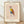 May include: Framed poster print leaning against white wall on light wood floor. Features geometric owl illustration in Picasso-inspired style with colorful triangular shapes in yellow, blue, and rust red. Simple line drawing with large circular eyes and thin legs. Text reads "PICASSO" at top and "The Met L'Art Minimaliste" at bottom. Light wood frame with cream matting on textured beige background.
