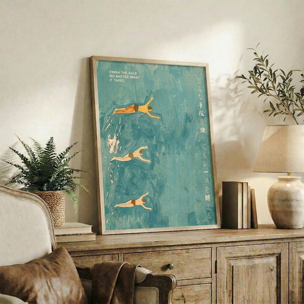 May include: Framed poster with turquoise blue background showing three orange-toned swimmers in diving poses, displayed on rustic wooden sideboard alongside potted plants, books, and ceramic vases in neutral-toned living room setting with cream chair visible.