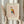 May include: Hands holding a framed poster featuring a geometric owl illustration in Picasso's minimalist style, with colorful triangular shapes in yellow, blue, and rust red against a cream background. The print shows "PICASSO" at top and "The Met L'Art Minimaliste" at bottom. Person wears beige clothing and holds dried pampas grass, photographed against white curtained window.