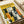 Stylized illustration of multiple cats in various colors and patterns arranged in a group composition. Features black, white, orange, and striped cats with simplified geometric forms and bold colors on a yellow background. The word "FELINES" appears at the top in black letters. Print is displayed flat on white paper with what appears to be a white tube or roll visible in the corner, suggesting this is the actual poster artwork rather than a room mockup.