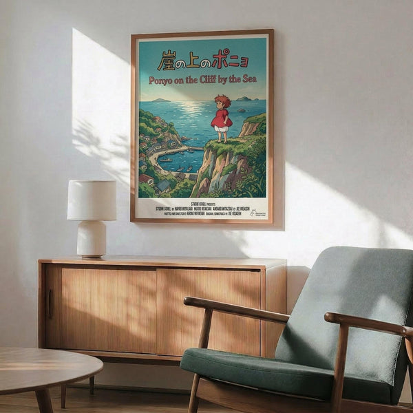 May include: Framed Studio Ghibli Ponyo movie poster hanging on white wall above wooden sideboard with lamp. Poster shows red-dressed girl on coastal cliff overlooking blue ocean with Japanese and English text. Mid-century modern furniture including teal upholstered chair with wood arms creates cozy living room setting with natural sunlight casting shadows.