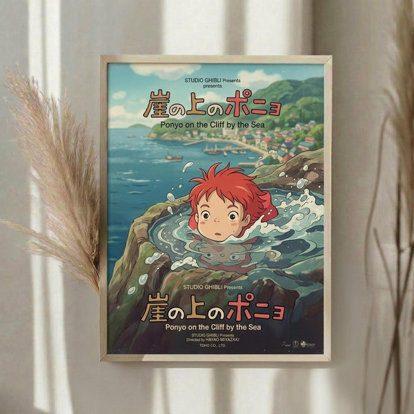 May include: Framed Studio Ghibli Ponyo movie poster displayed on white wall next to dried pampas grass. Poster shows red-haired Ponyo character in ocean water with Japanese text and "Ponyo on the Cliff by the Sea" title. Artwork features coastal village background with blue-green water, splashing waves, and anime illustration style in thin gold frame.