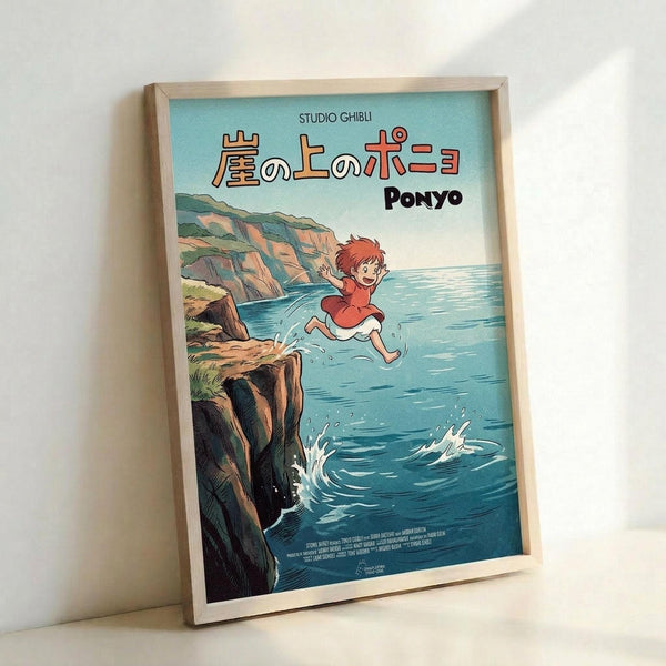A framed Studio Ghibli Ponyo movie poster featuring the red-haired character jumping over blue ocean water near rocky coastal cliffs. The anime-style artwork shows Japanese text at the top with "PONYO" in English below. The poster has a light blue sky background and is displayed in a natural wood frame leaning against a white wall, creating soft shadows.