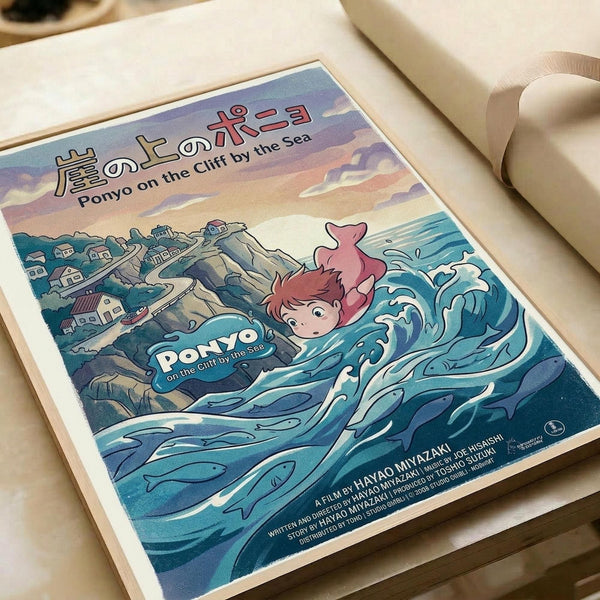 May include: Studio Ghibli-style poster print featuring red-haired Ponyo character emerging from stylized blue ocean waves. Coastal village with small houses sits on rocky cliffs under a sunset sky with pink and purple clouds. Japanese and English text at top reads "Ponyo on the Cliff by the Sea." Print displayed on light wooden surface with white rolled paper in background. Artwork shows vibrant blues, corals, and earth tones in anime illustration style.