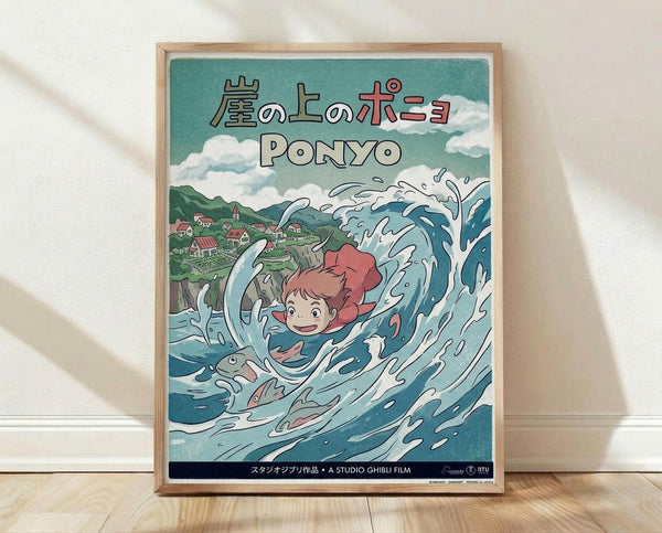 May include: Framed Studio Ghibli Ponyo movie poster in light wood frame, leaning against white wall on wooden floor. Poster features red-haired girl character swimming in stylized blue ocean waves with fish, overlooking coastal village with green hills. Japanese text at top, turquoise sky with white clouds, vibrant anime art style with Studio Ghibli film branding at bottom.