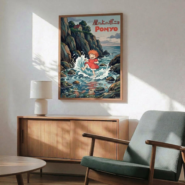 May include: Framed Ponyo movie poster displayed on white wall above wooden credenza with table lamp. Shows young girl with orange hair running through ocean waves between rocky cliffs, with house visible on clifftop. Mid-century modern room setting features green upholstered chair with wooden arms and round coffee table. Natural lighting creates shadows across minimalist interior.