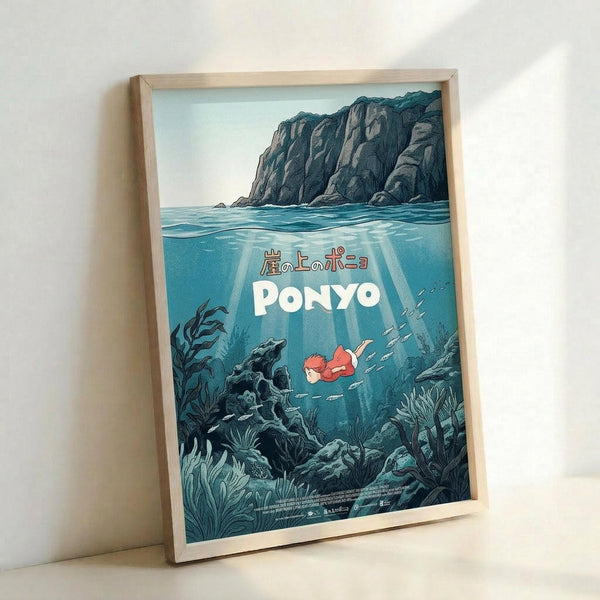 May include: Framed poster print leaning against white wall showing underwater scene with small red-haired character swimming among sea plants and fish. Blue-green ocean water with rocky cliffs above surface, Japanese text and "PONYO" in white letters. Light wood frame, soft natural lighting casting gentle shadows.