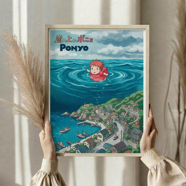 May include: Person holding framed Ponyo poster print in light wood frame against white curtained window, dried pampas grass beside them. Artwork shows anime character Ponyo floating in ocean waves above coastal Japanese village with boats, mountains, and traditional buildings. Vibrant blues, greens, and coral colors in Studio Ghibli animation style.