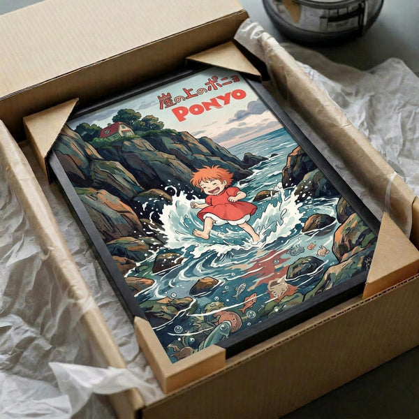 May include: Framed anime-style poster showing red-haired child character splashing in ocean water surrounded by rocky coastline. Artwork features Studio Ghibli animation style with Japanese text at top. Black frame sits in opened cardboard shipping box with protective wrapping paper on wooden surface.