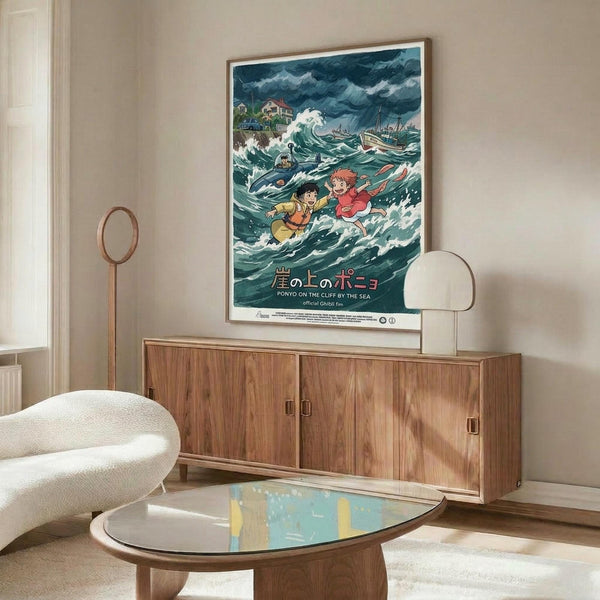 May include: Framed Studio Ghibli Ponyo movie poster displayed above a wooden mid-century modern credenza in a minimalist living room. The colorful anime artwork shows characters in stormy ocean waves with Japanese text. White curved chair and glass coffee table visible in foreground. Clean aesthetic with beige walls and natural lighting.