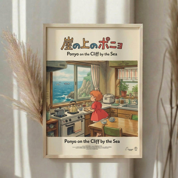 May include: Framed Studio Ghibli movie poster showing young girl with red hair in red dress cooking in cozy kitchen overlooking ocean cliffs. Artwork features warm colors, wooden kitchen with stove and window view of blue sea. Light wooden frame displayed on white wall next to dried pampas grass decoration with natural window lighting.