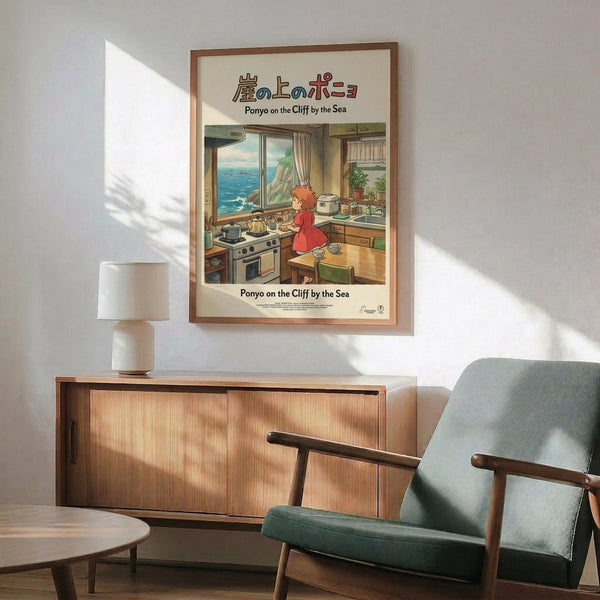 May include: Framed Studio Ghibli Ponyo poster mounted on white wall above wooden credenza with small ceramic table lamp. Green mid-century modern armchair with wooden arms sits nearby next to small round side table. Poster shows red-haired character in cozy kitchen overlooking blue ocean through large windows. Natural sunlight creates diagonal shadows across the minimalist room setting.