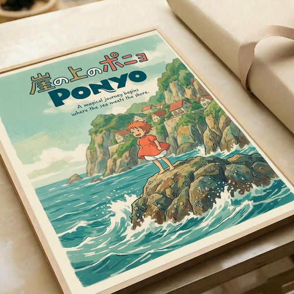 Studio Ghibli-style poster showing red-haired Ponyo character standing on a large fish emerging from turquoise ocean waves. Japanese text at top with English subtitle "A magical journey begins where the sea meets the shore." Coastal cliffs and village visible in background under soft green sky. Vintage anime art style with warm, whimsical illustration. Print displayed in wooden frame on white surface.
