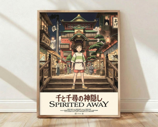 May include: Framed Spirited Away movie poster showing young girl Chihiro in green and white striped shirt standing on wooden steps facing a magical Japanese bathhouse town at night. Traditional architecture with lanterns, wooden buildings, and spirits visible in background. Poster displayed in light wood frame leaning against white wall on wooden floor with natural lighting and shadows.