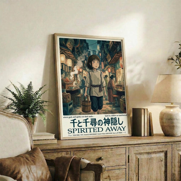 May include: Framed Spirited Away movie poster in light wood frame displayed on rustic wooden sideboard next to fern plant, cream throw pillow, and ceramic vases. Poster shows anime girl character in bustling Japanese street market scene with lanterns and traditional architecture in teal and warm tones.