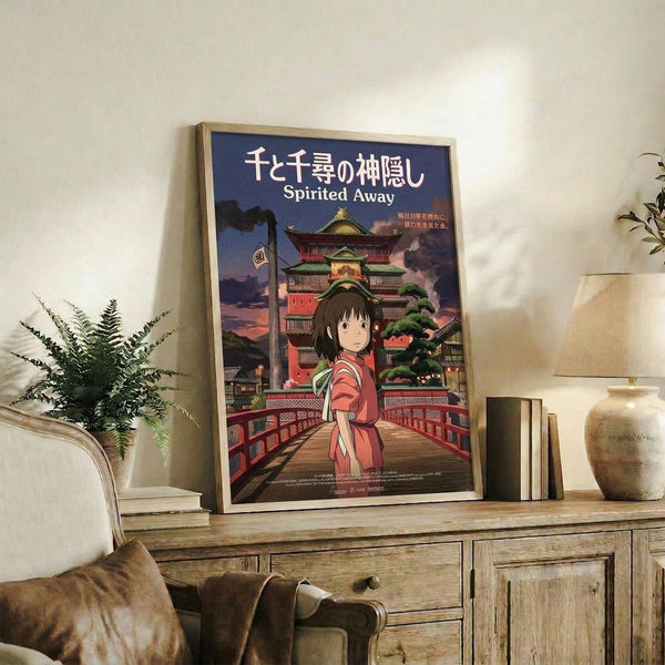 May include: Framed Spirited Away movie poster featuring anime character Chihiro in red outfit standing on wooden bridge with traditional Japanese bathhouse in background, displayed on rustic wooden sideboard next to fern plant, books, and ceramic vase in cozy living room setting with beige armchair