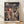 May include: Framed Studio Ghibli Spirited Away movie poster featuring anime girl with short reddish-brown hair in burgundy outfit standing before elaborate Japanese bathhouse with traditional architecture, bridges, and crowds of people. Poster displays both Japanese and English text against dramatic cloudy sky. Natural wood frame sits on light wooden floor against white wall with soft shadows.