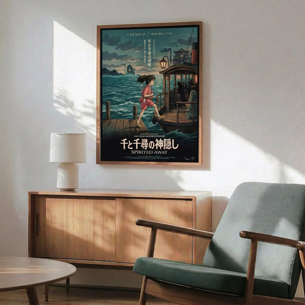 May include: Framed Studio Ghibli Spirited Away movie poster mounted on white wall above wooden sideboard. Poster shows young girl on wooden dock near traditional boat with pagoda in background, featuring teal water and cloudy sky. Mid-century modern room setting with gray upholstered chair, round coffee table, and ceramic table lamp casting natural shadows.