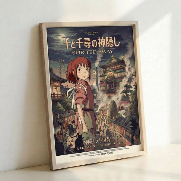 May include: Framed Spirited Away movie poster featuring main character Chihiro in traditional red outfit standing before fantastical Japanese architecture with pagodas, bridges, and spirit world buildings. Poster displays Japanese and English text including "Studio Ghibli Present" at top. Light wood frame sits against white wall with soft lighting creating gentle shadows.