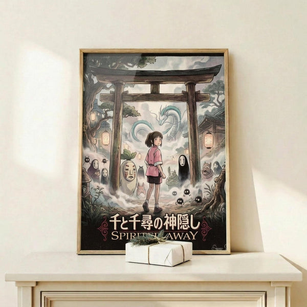 May include: Framed Spirited Away movie poster displayed on light wood shelf against white wall. Artwork shows young girl in pink shirt standing under traditional Japanese torii gate, surrounded by spirits including No-Face and Haku dragon in misty clouds. Japanese and English title text at bottom. Small white wrapped gift box sits on shelf beside the wooden-framed print.