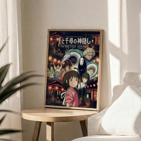 May include: Framed Studio Ghibli Spirited Away anime poster displayed on a light wood round side table next to a beige upholstered chair. The colorful poster features the main character Chihiro in a red shirt surrounded by various magical characters including No-Face, Haku the dragon, and other spirits from the bathhouse. Japanese text appears at the top with "SPIRITED AWAY" in English below. Natural sunlight streams across the minimalist room setting with a plant visible in the corner.