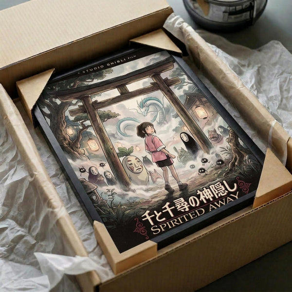 May include: Studio Ghibli Spirited Away poster in wooden frame, packed in brown cardboard box with protective wrapping. Artwork shows young girl Chihiro in pink sweater surrounded by iconic characters including No-Face, dragon Haku, and various spirits in traditional Japanese building setting. Vintage-style illustration with muted earth tones and magical fantasy elements.