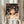 May include: Framed Spirited Away movie poster held by hands wearing cream ruffled sleeves, featuring anime girl Chihiro with dark hair surrounded by white spirits against mystical bathhouse background. Japanese and English text visible at bottom. Dried pampas grass and neutral curtains create soft, aesthetic room setting.