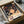 May include: Spirited Away anime poster print featuring young Chihiro with brown hair and green shirt against a magical bathhouse background with floating spirits and warm lighting. The framed artwork sits in an open cardboard shipping box with white tissue paper padding on a marble surface.