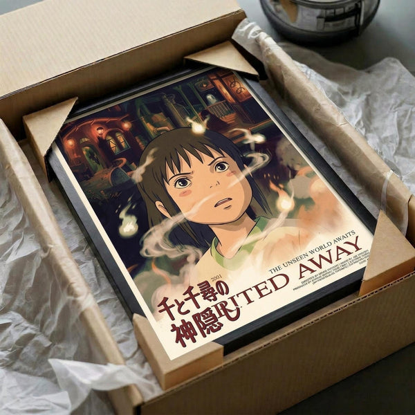 May include: Spirited Away anime poster print featuring young Chihiro with brown hair and green shirt against a magical bathhouse background with floating spirits and warm lighting. The framed artwork sits in an open cardboard shipping box with white tissue paper padding on a marble surface.