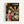 Framed poster featuring animated characters from Studio Ghibli's Spirited Away. Shows a young girl with dark hair in a red outfit on the left, standing in a traditional Japanese street lined with paper lanterns. Behind her are various colorful spirits and creatures including No-Face, a large white radish spirit, and other magical beings. The scene depicts a bustling bathhouse district with warm golden lighting. Japanese text appears at the top with "Spirited Away" in English below. The poster